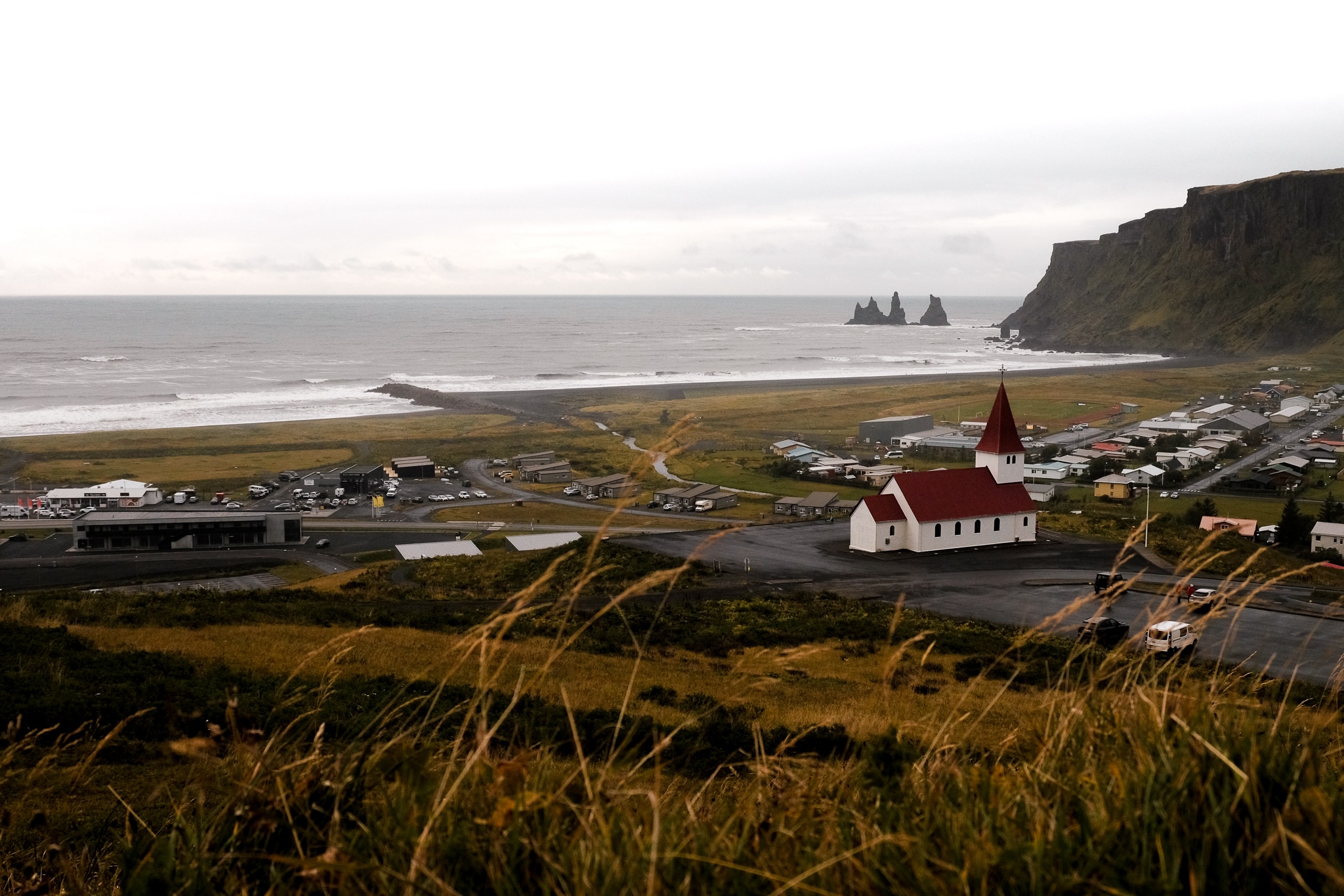 Vik from the mountain side showing off it's beautiful white church with a red roof, the black beach in the distance