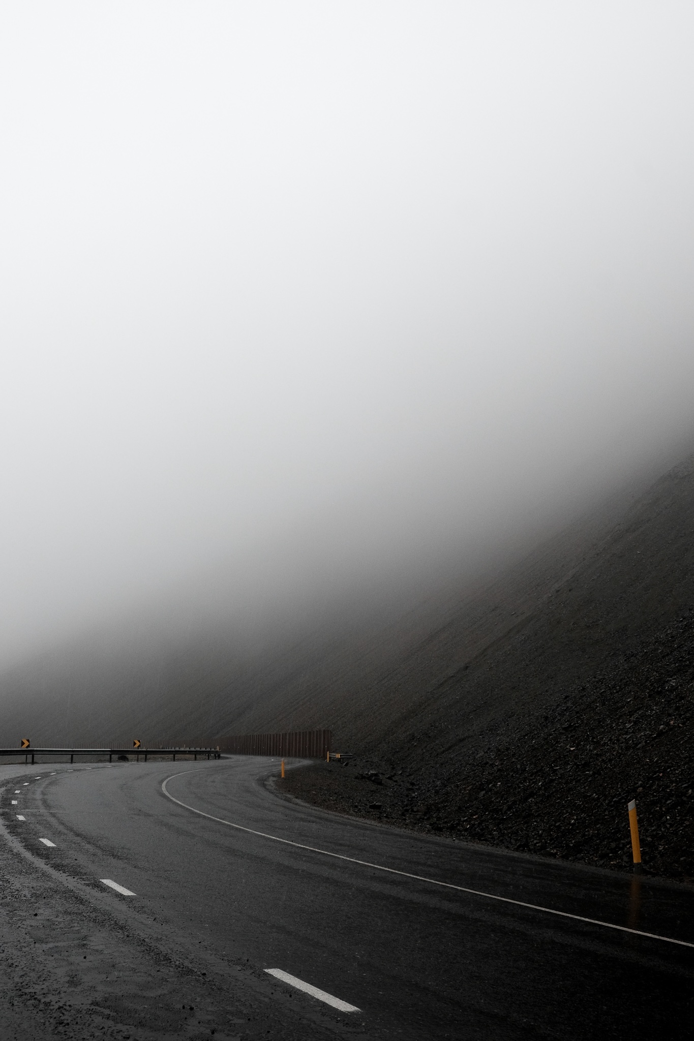 A mountain pass road, raining and covered with mist