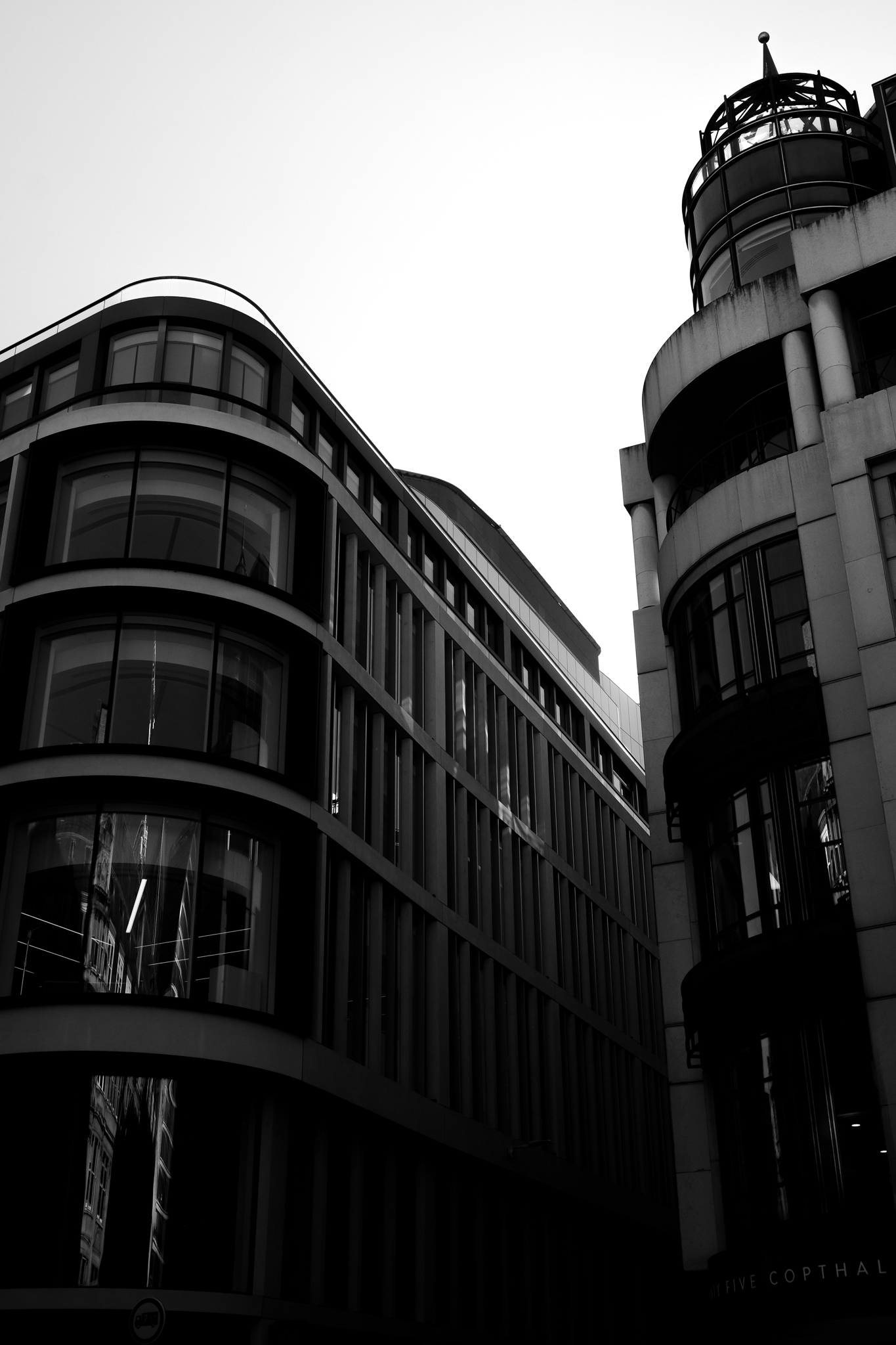 Black and white image of two buildings corners that are rounded off perfectly