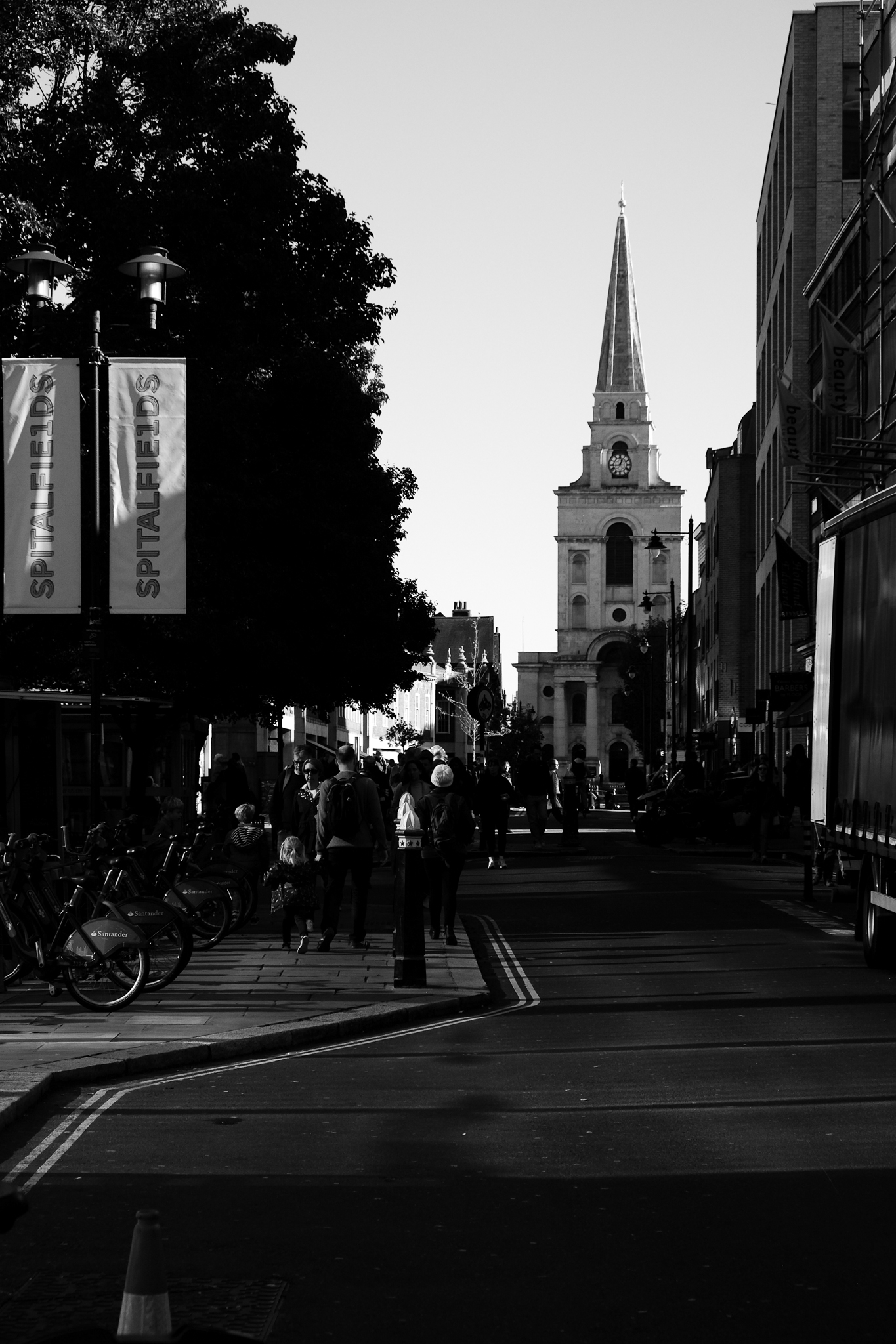 Black and white image down the street of the entrance to Spitalfields market with the church tower at the end of the road
