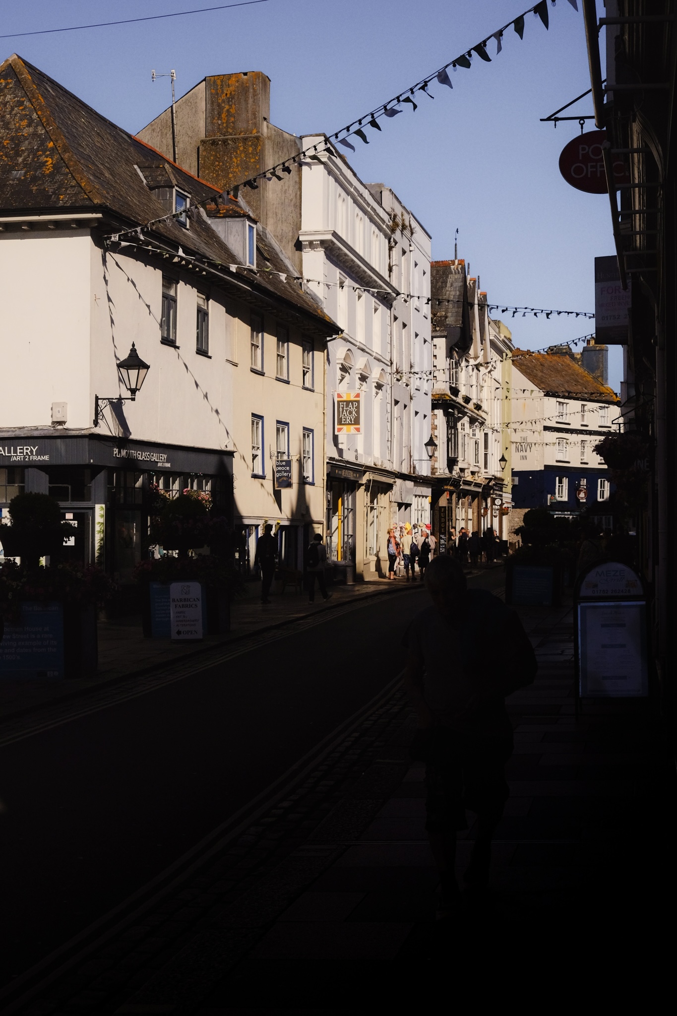 Plymouth waterfront cobbled street lined with restaurants and bunting strung across the road