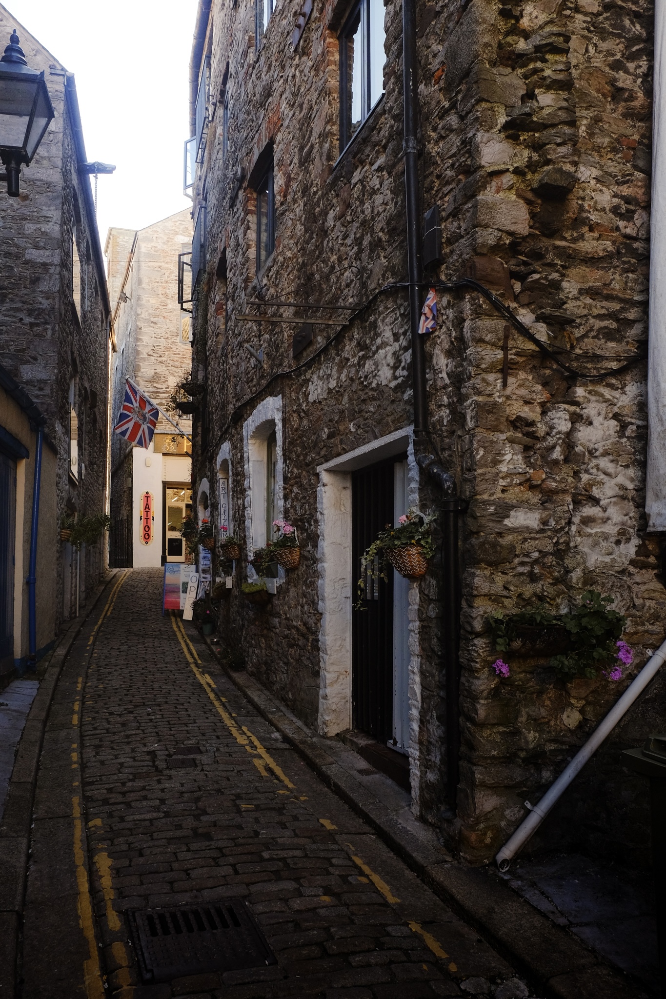 A narrow street with stone buildings, the harsh sun shining through between them