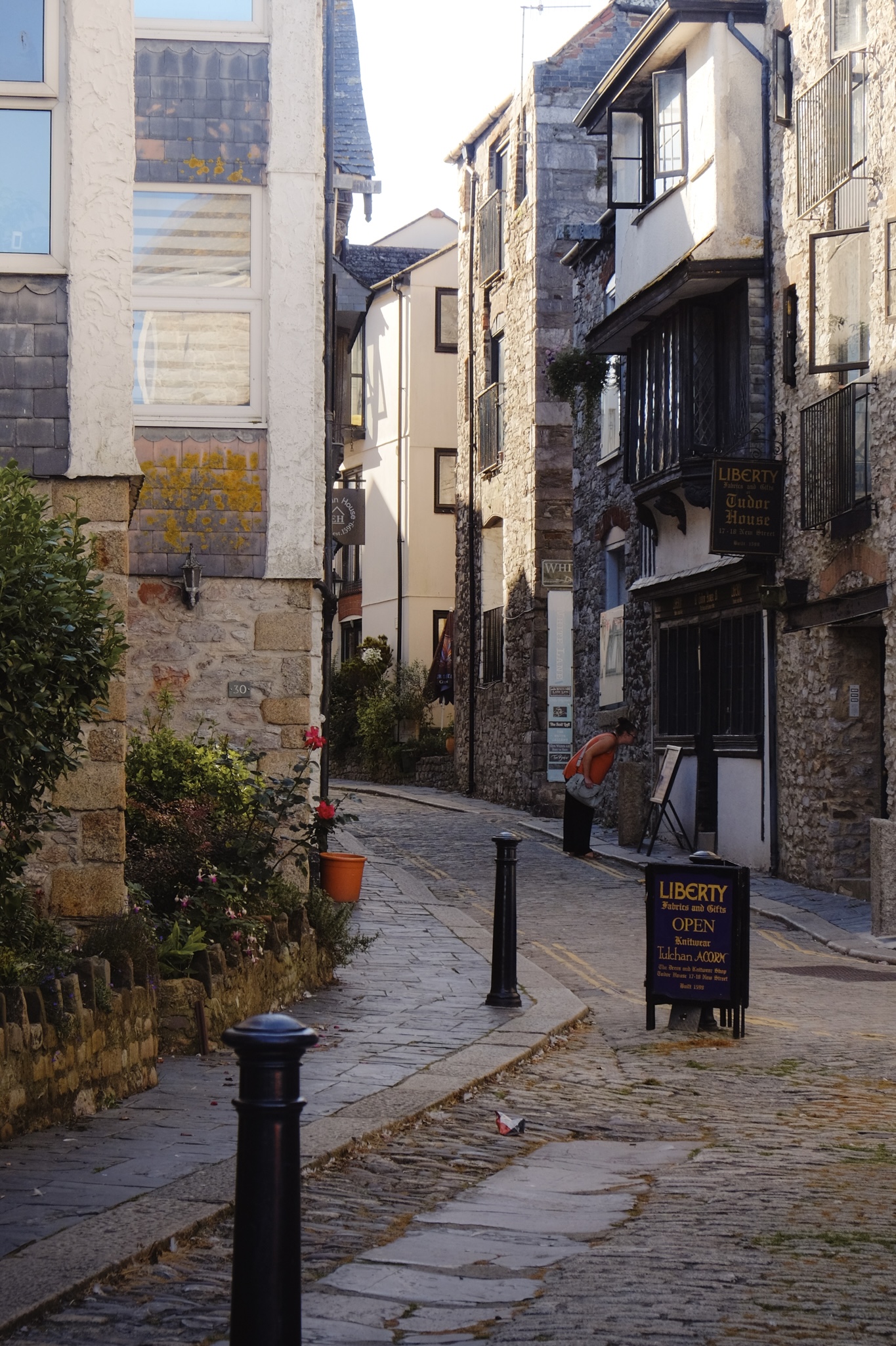 A solitary women examines a restaurant menu on a cobbled street in Plymouth