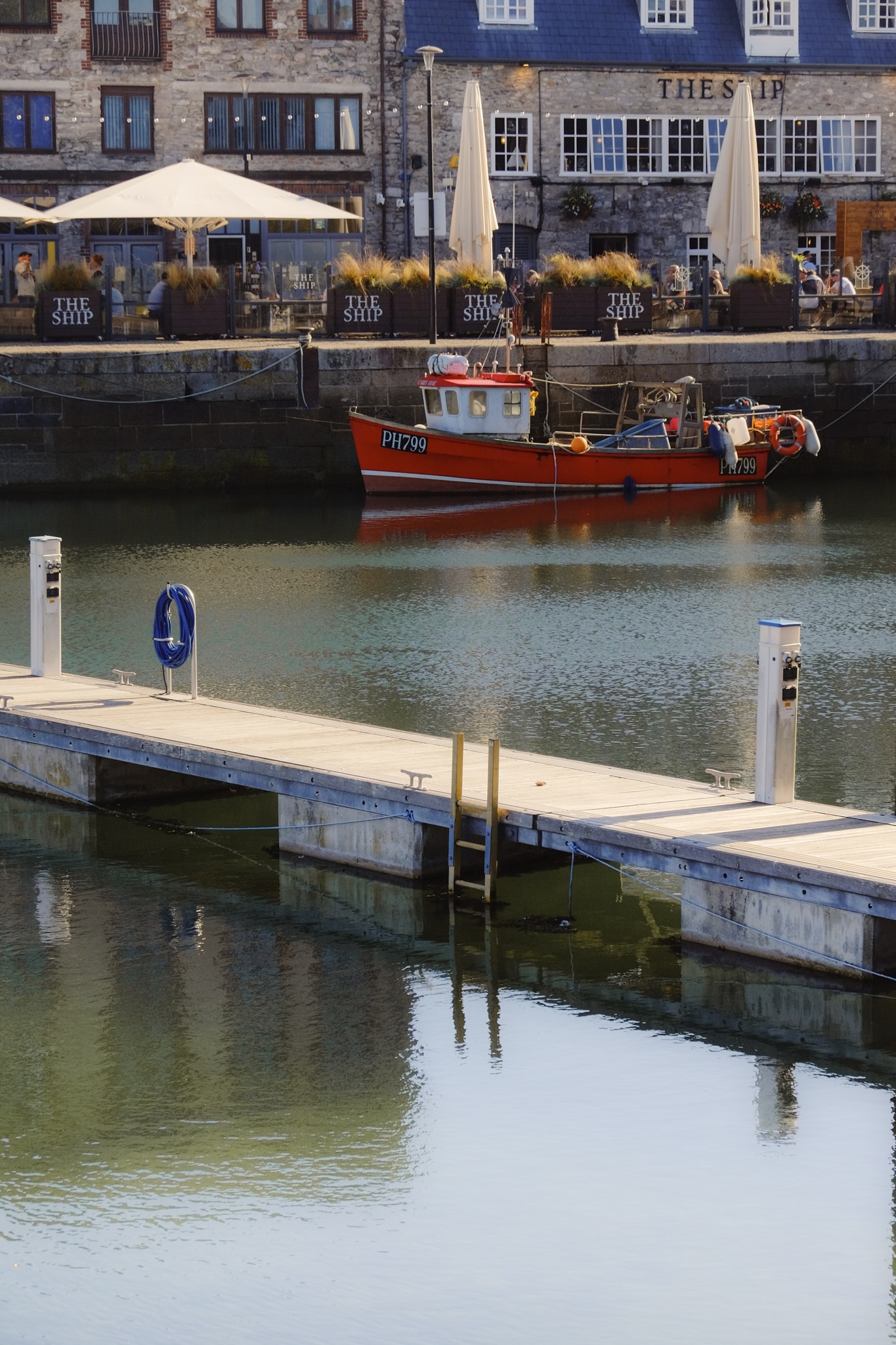 A red boat moored in a waterfront with restaurants behind