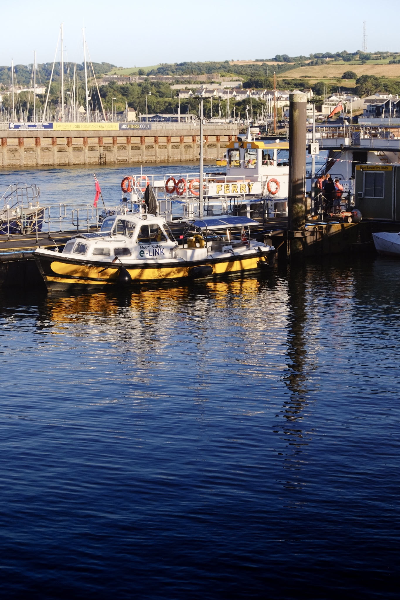 The yellow mount batten electric ferry moored at the harbour in deep blue water