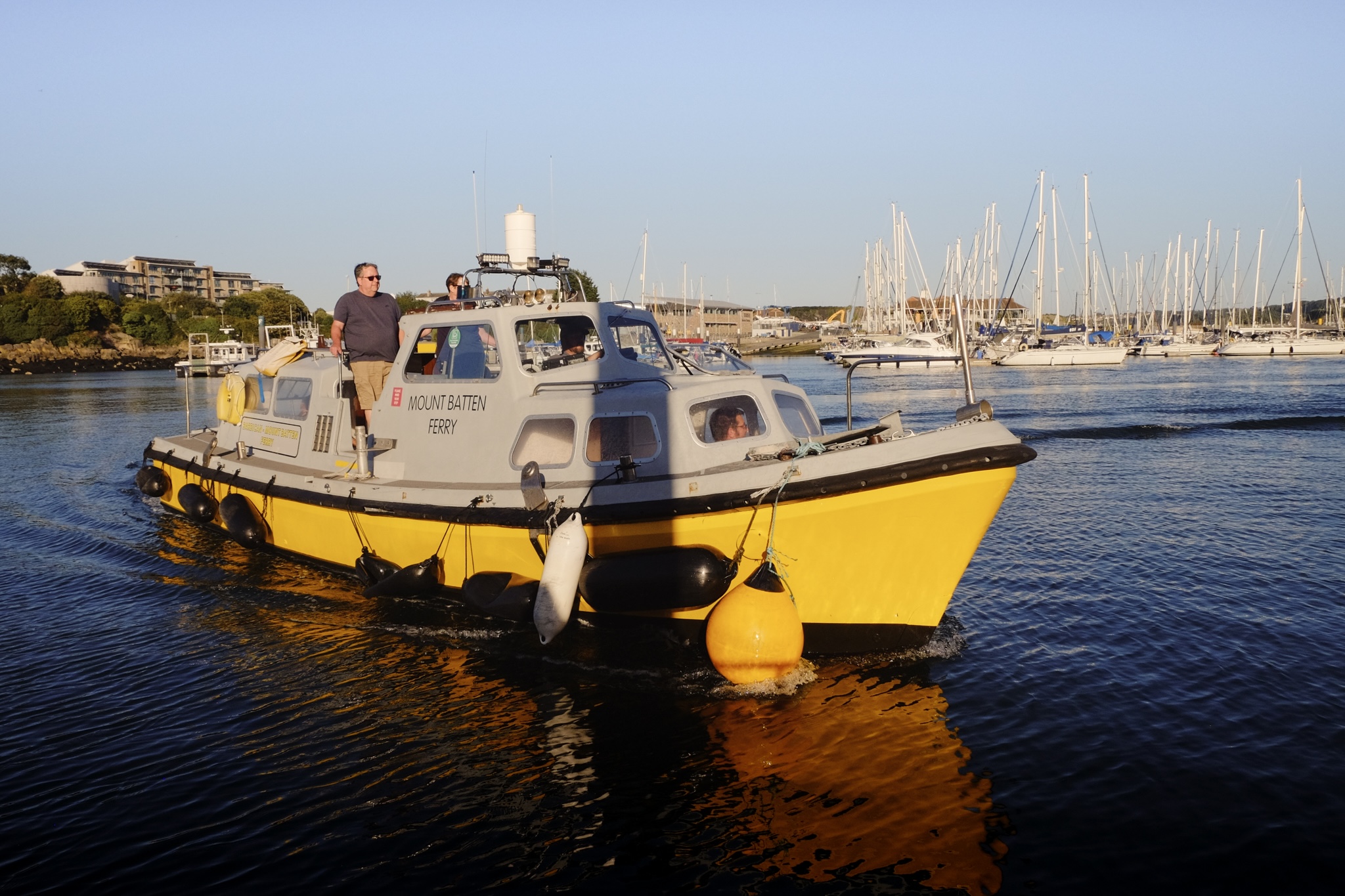 A yellow mount batten small vessel approaching the jetty in the harbour