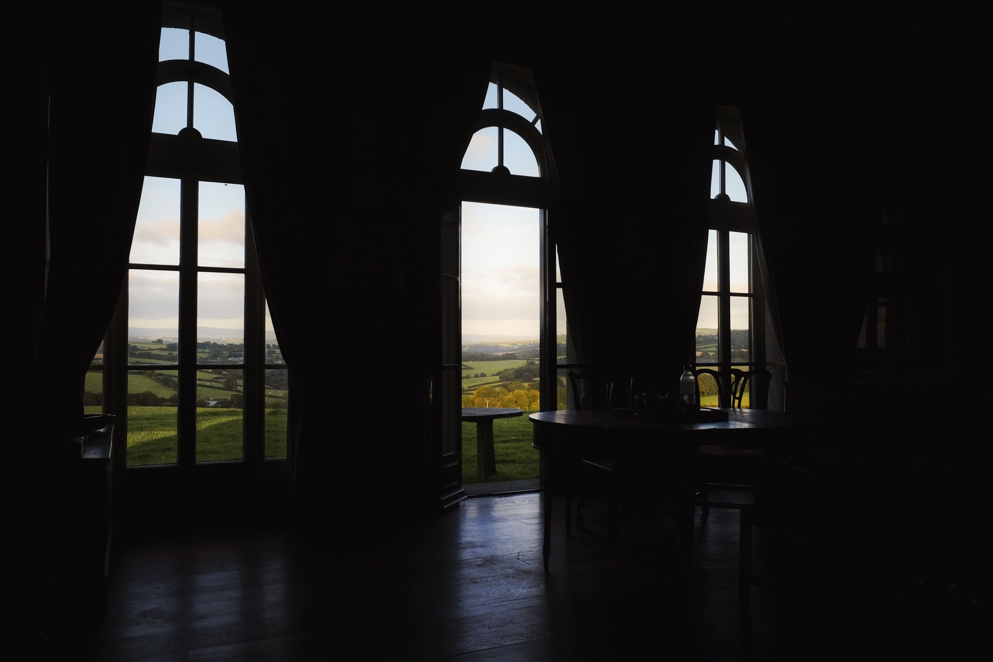 Inside a house looking out the window to cornwall farm land