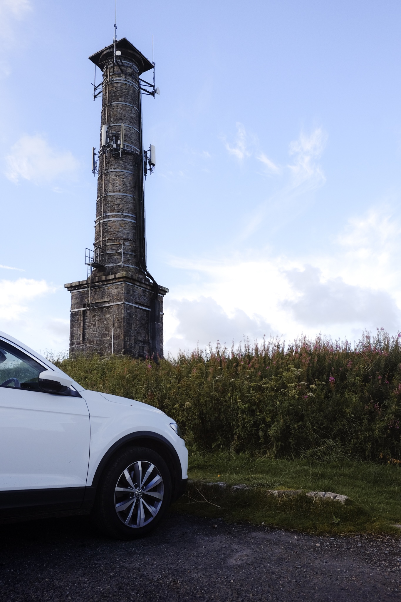 The Kit hill radio tower next to our VW T-Roc against a blue sky