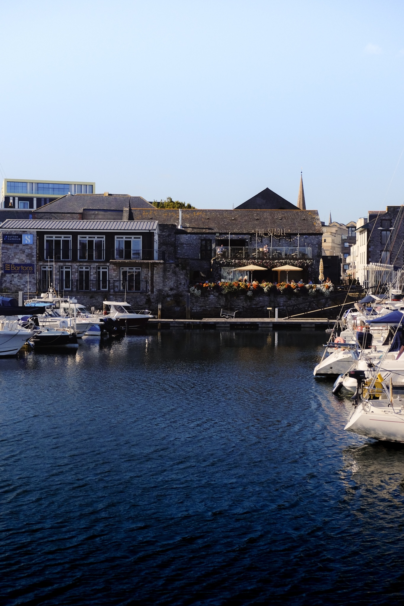 Restaurant with flower boxes across the waterfront with boats