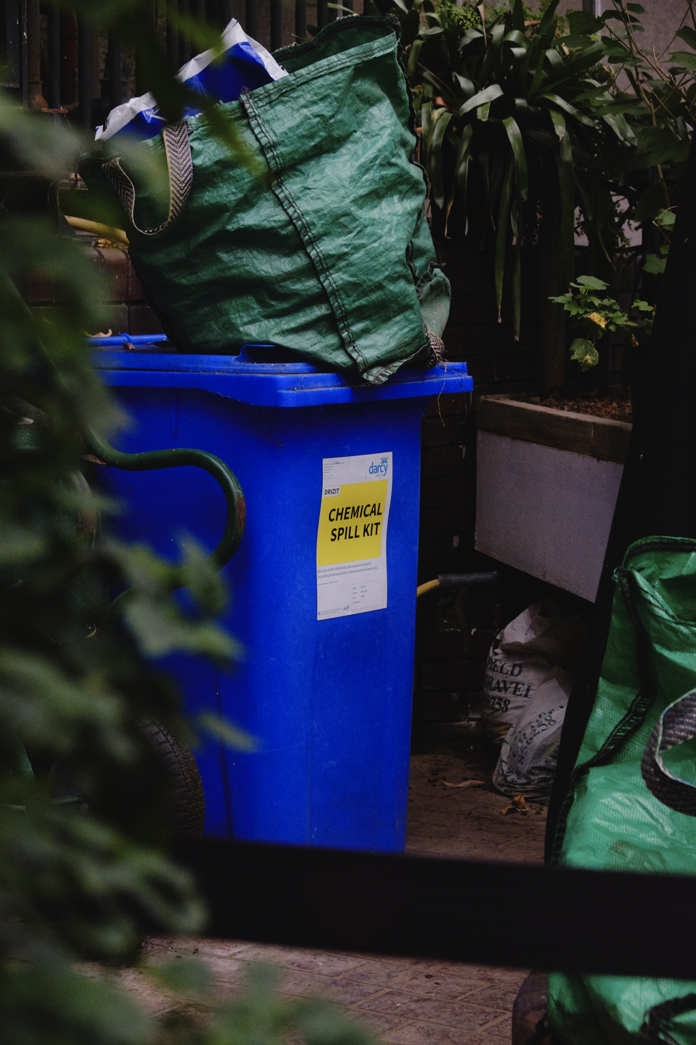 Stark, garden waste blue bin in a cornered off area